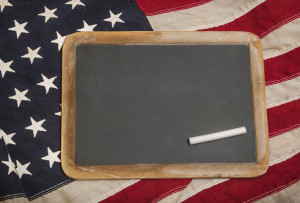 Small chalkboard with a piece of chalk sitting on an American flag